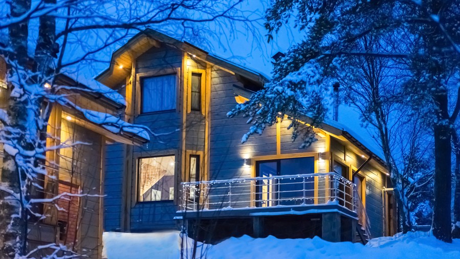 Photo of a beautifully lit home exterior at night with snow coverage.